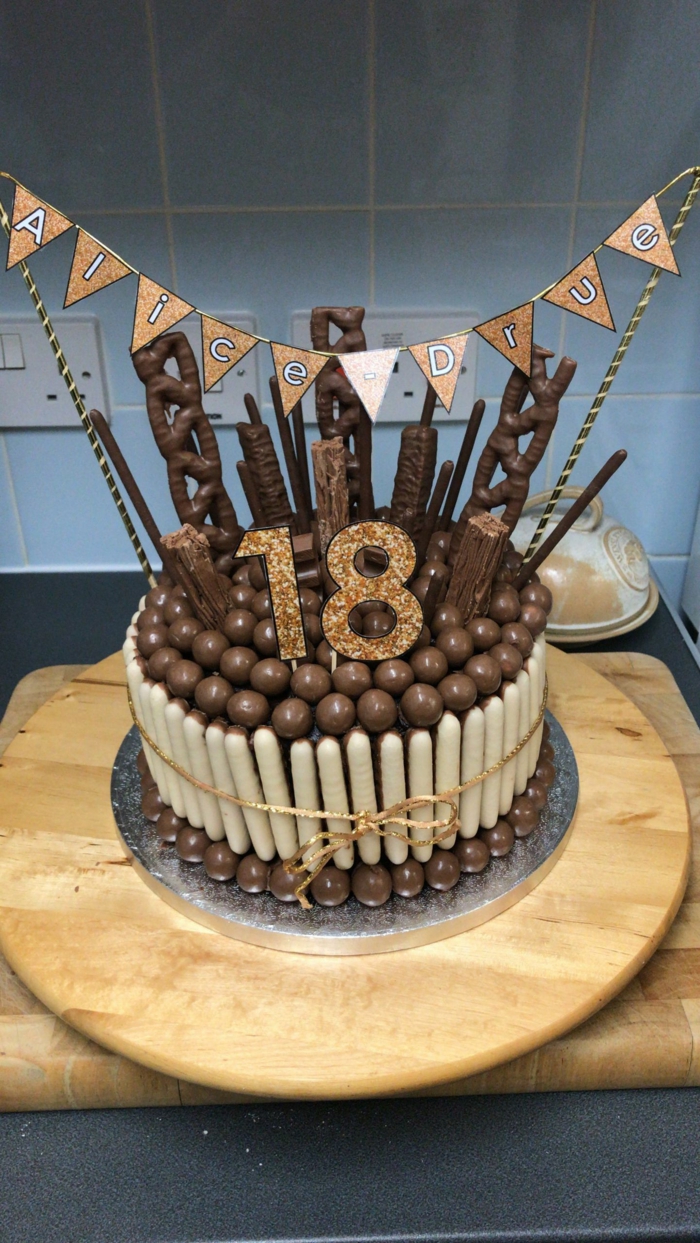 cake made of chocolate candy, surprise party ideas, placed on wooden board, alice drue banner on top