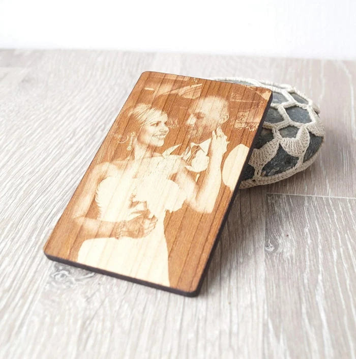 photo of the bride and groom, printed on a wooden coaster, anniversary gifts for her, placed on wooden surface
