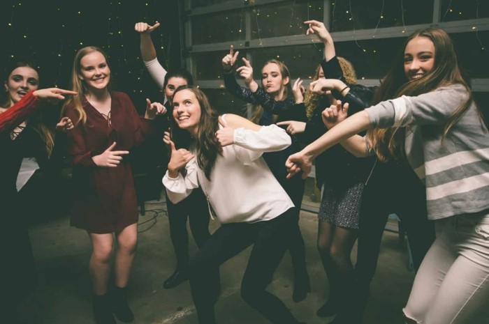 seven girls posing for a photo, smiling and dancing, things to do on your 18th birthday, wearing different outfits