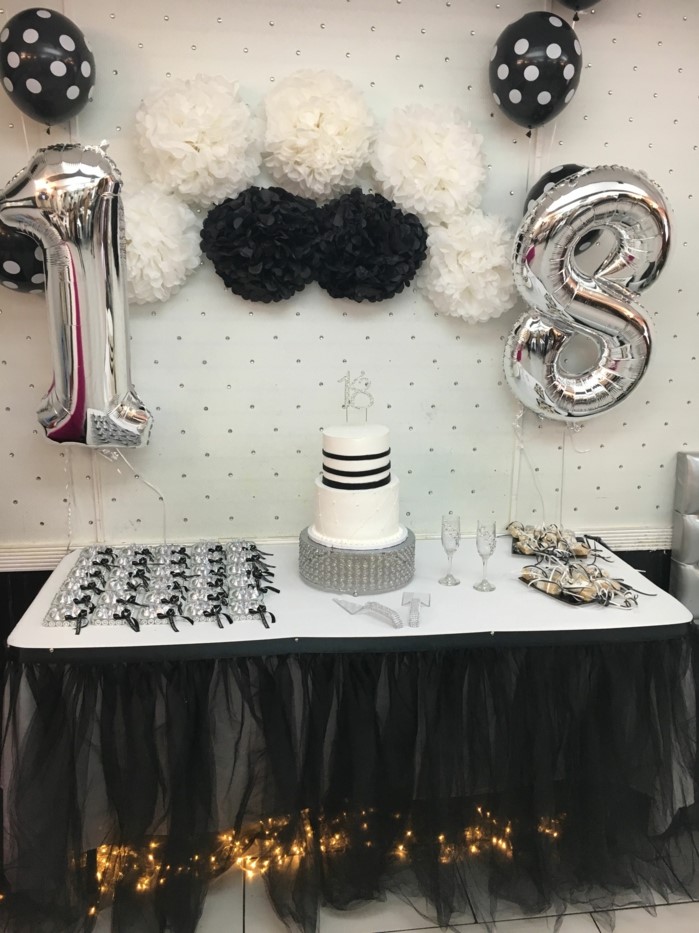 black and white paper flowers on white wall, silver number 18 balloons, hanging over desserts table