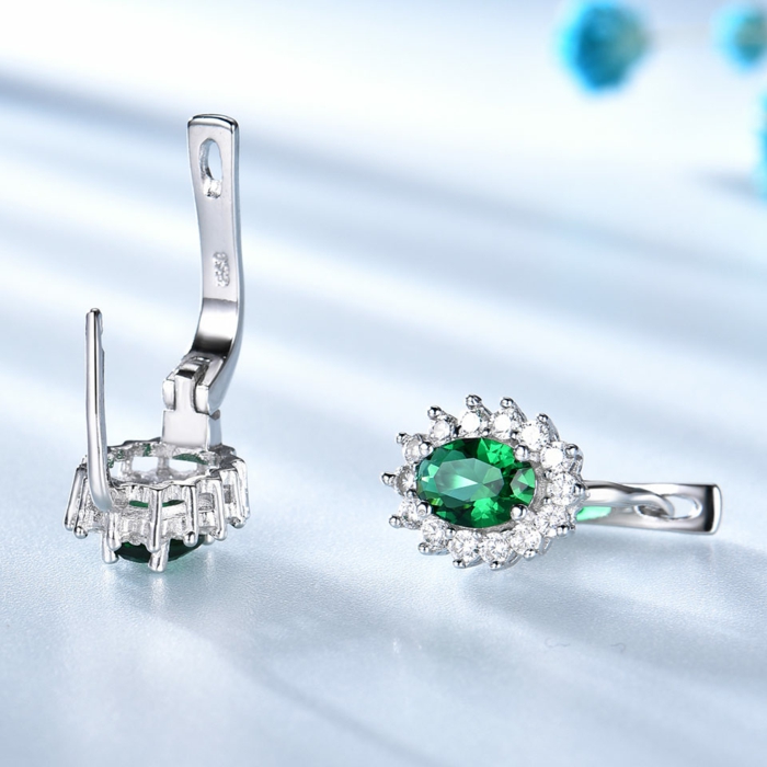 silver earrings with emerald crystals and rhinestones, traditional wedding anniversary gifts, placed on white surface