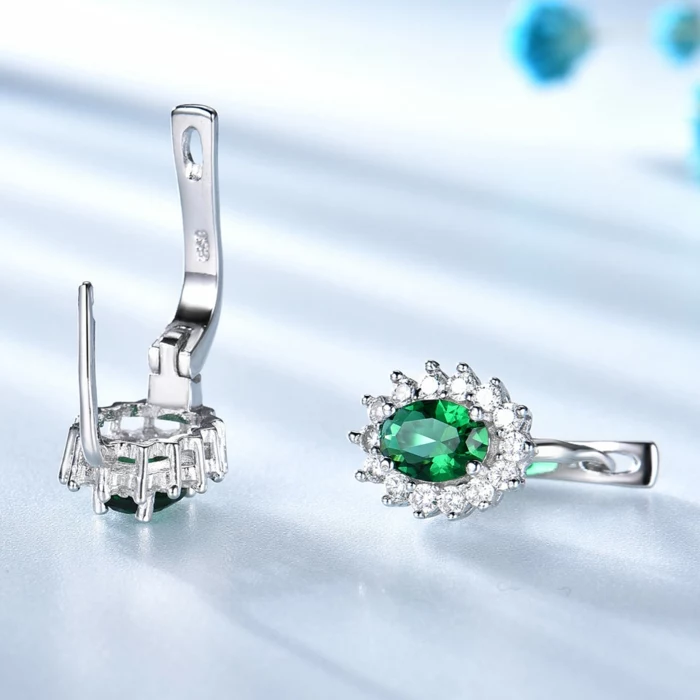 silver earrings with emerald crystals and rhinestones, traditional wedding anniversary gifts, placed on white surface
