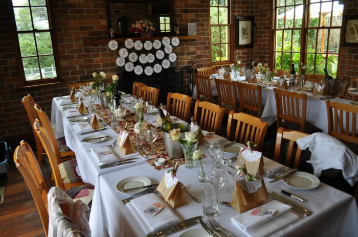 long wooden tables, decorated with white roses, 80th birthday gift ideas for mom, plates and glasses