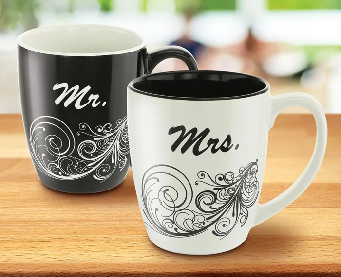 two coffee mugs, black and white for the mr and mrs, 40th anniversary gifts, placed on wooden surface