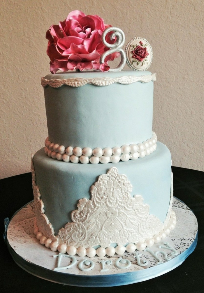 two tier cake, covered with blue fondant, lace and perls made of white fondant, 80th birthday party favors