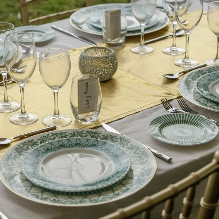 china dinner set, placed on table with grey tablecloth and gold table runner, wedding anniversary gifts by year, wine glasses and utensils
