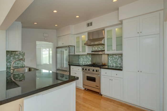 green and white mosaic backsplash, mid century modern floor tile, white cabinets with black countertops