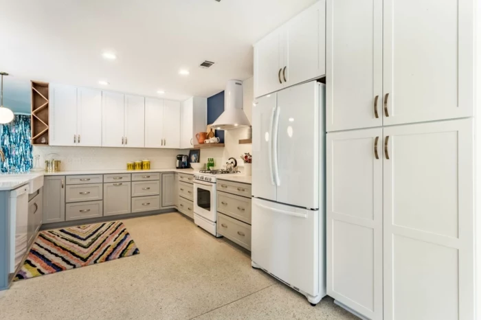 mid century modern backsplash tile, light grey cabinets with white countertops, tiled floor with rug