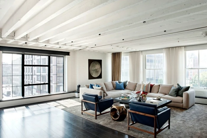 white corner sofa, two black leather armchairs, modern living room decor ideas, dark wooden floor with grey carpet