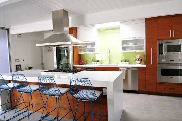 wooden kitchen island, wooden cabinets with white countertops, blue bar stools, mid century modern backsplash tile