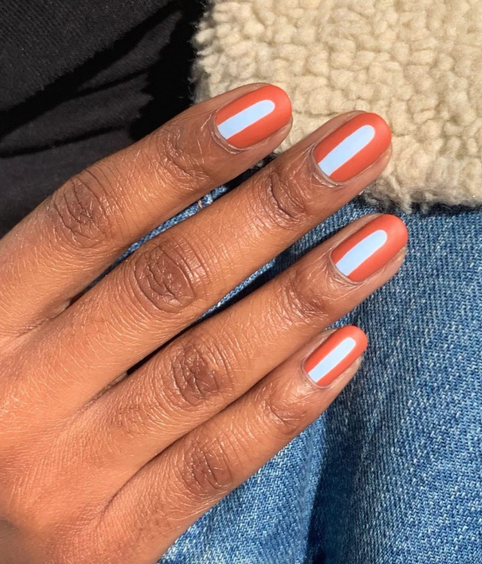 short squoval nails, orange nail polish, blue lines decorations in the middle, summer nail designs