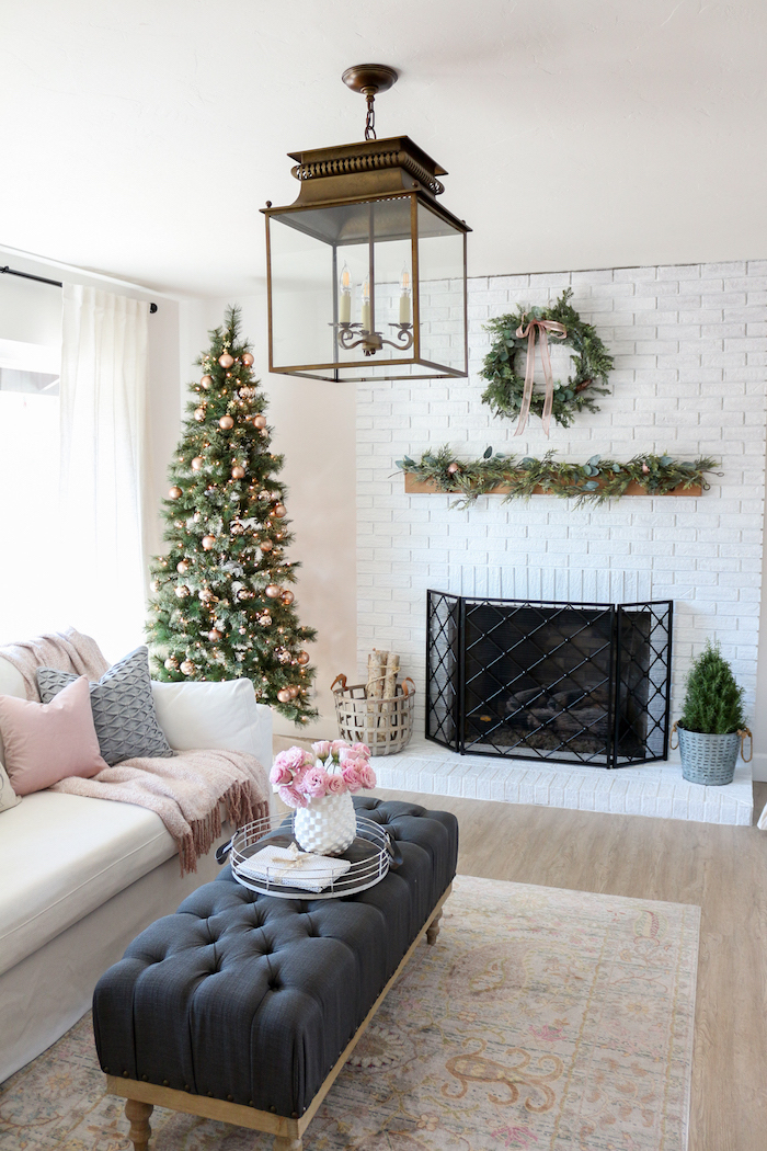 christmas tree in the corner, farmhouse living room, black ottoman and white sofa, placed in front of a fireplace