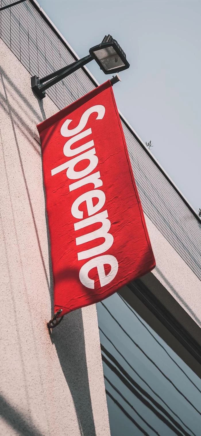 black supreme wallpaper photo taken outside of supreme store with a flag of the logo in red and white