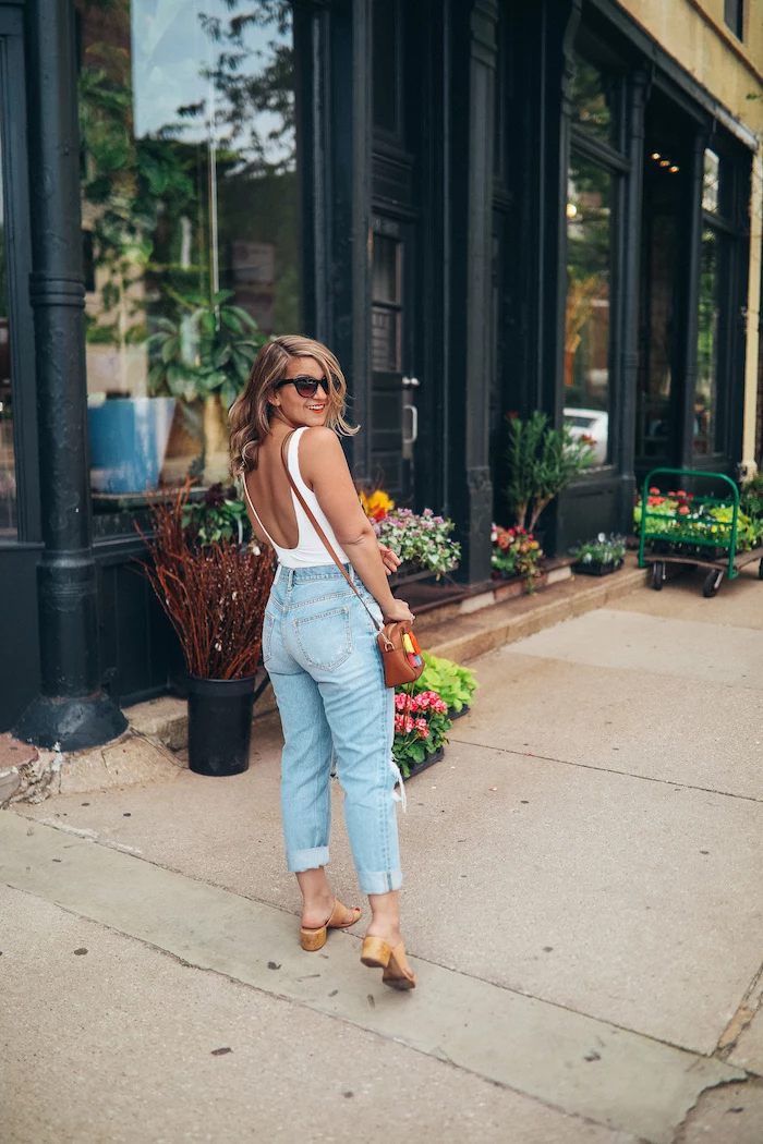 blonde woman wearing jeans and white top with bare back cute summer outfits for teens brown leather crossbody bag and sandals