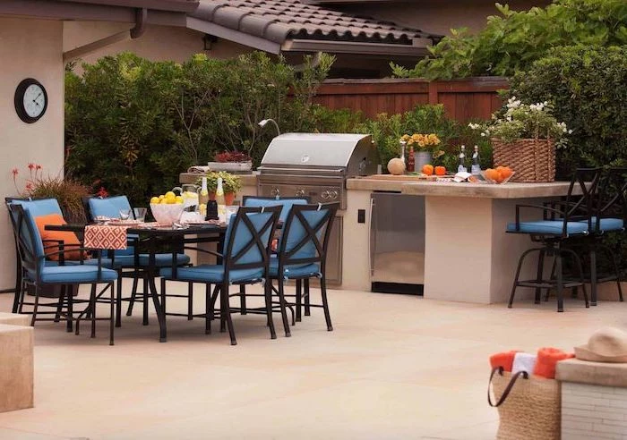 blue chairs around black dining table outdoor grill station barbecue and fridge stone countertops tiled floor