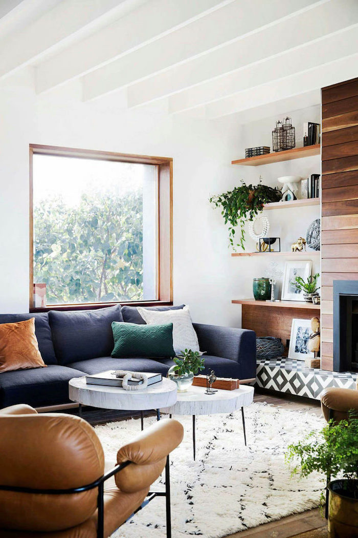 blue sofa with small coffee table, brown leather armchair, wooden bookshelves and fireplace, farmhouse decor