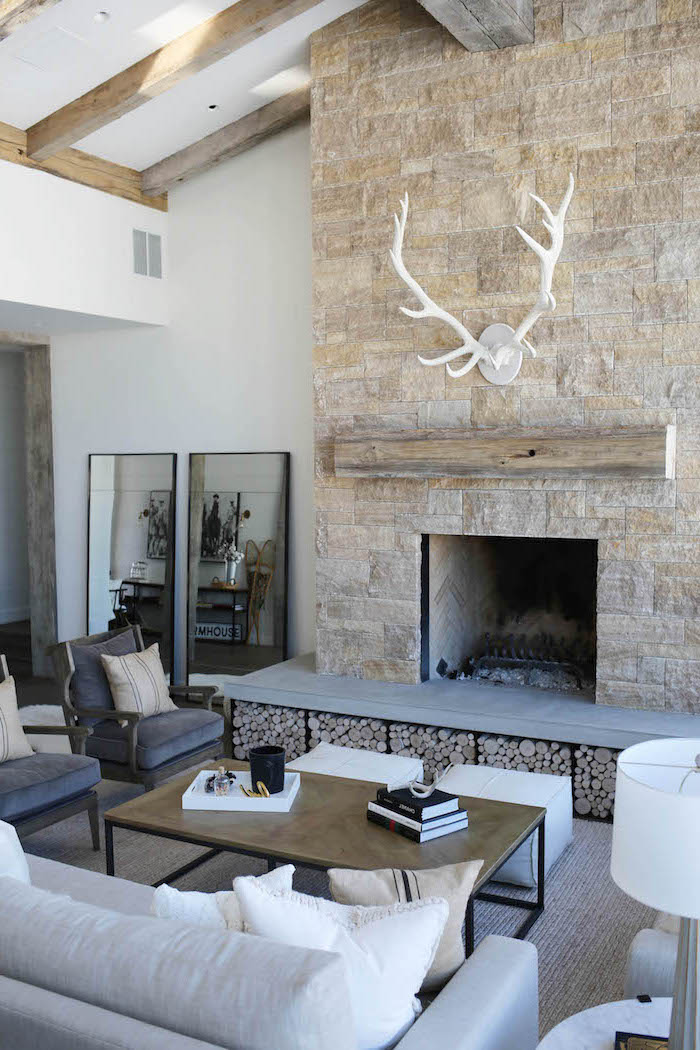 stone wall fireplace, modern farmhouse decor, grey armchairs and white sofa, placed in front of it, white carpet