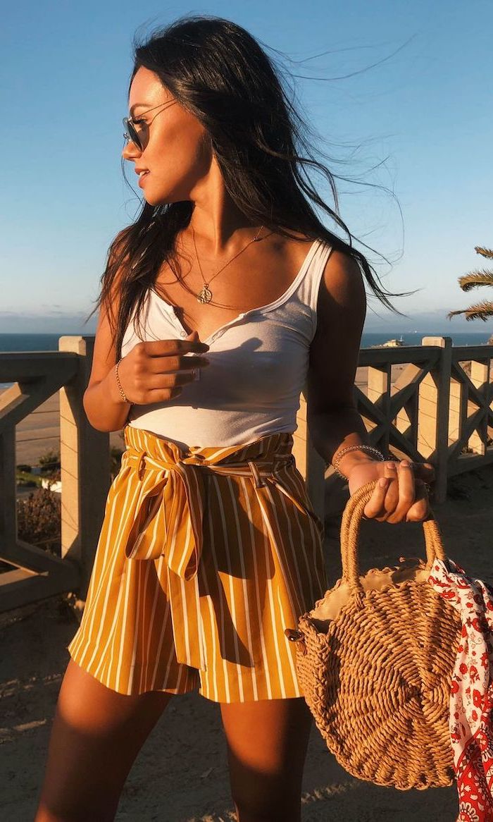 brunette woman wearing orange and white striped shorts white top cute simple outfits with sunglasses