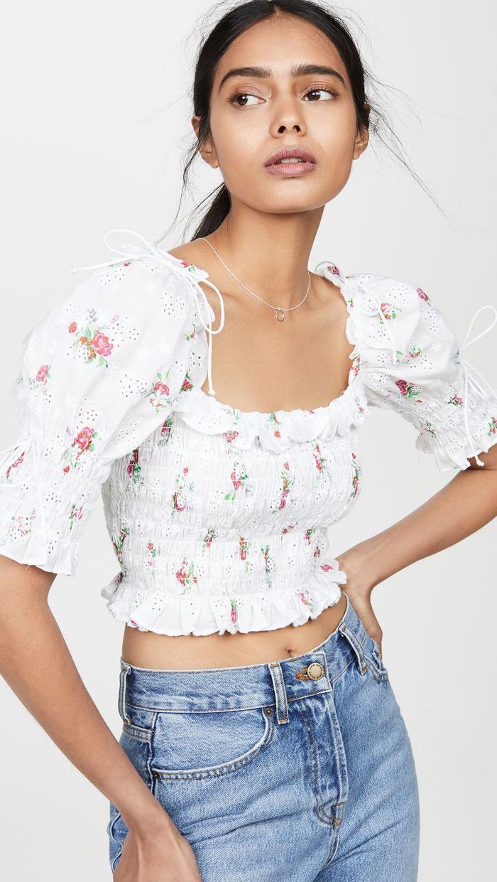 brunette woman with hair in ponytail cute trendy outfits wearing white floral crop top high waisted jeans