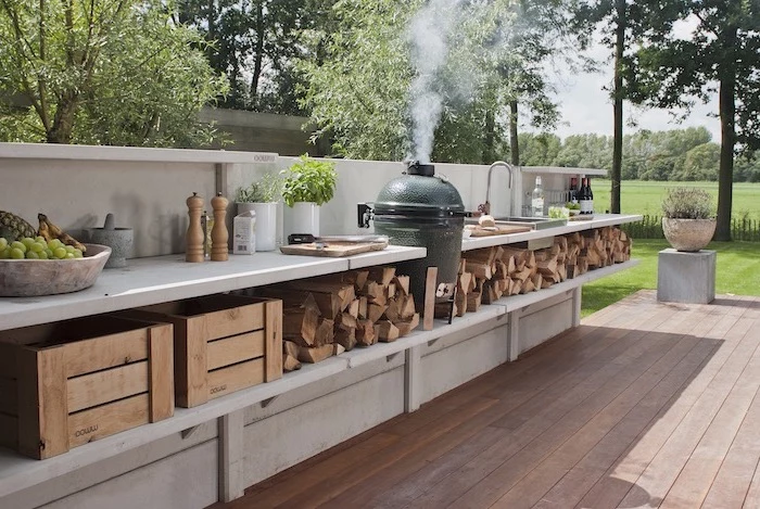 built in grill open shelves with wood logs under white countertops l shaped outdoor kitchen wooden floor