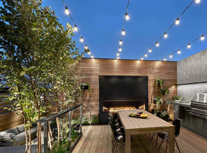 dinig table made of wood with black chairs next to fireplace outdoor bbq ideas metal kitchen cabinets with grill strings of lights hanging above