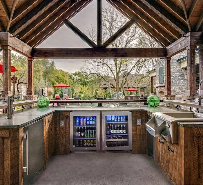 drinks fridge and wooden cabinets with marble countertop backyard kitchen ideas wooden caulted ceiling kitchen next to the pool