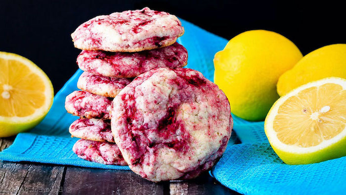 easy summer desserts cookies made with raspberries and lemons arranged on blue cloth halved lemons around them
