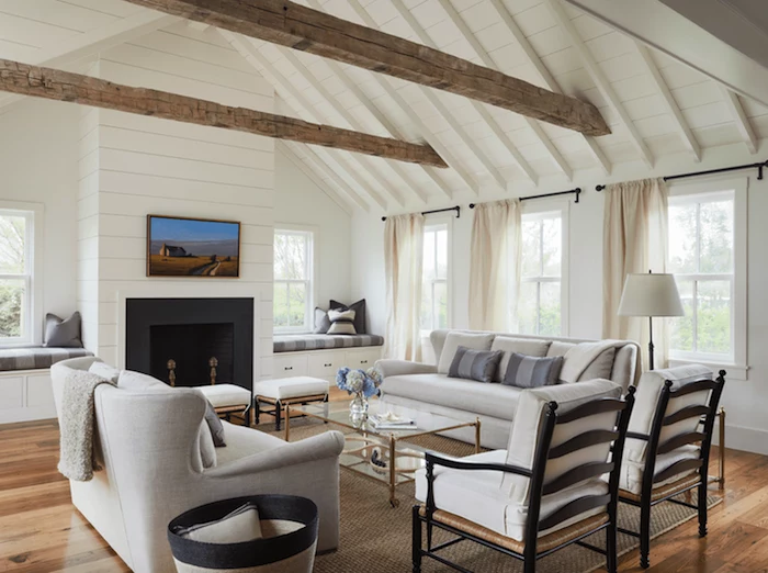 white furniture set, placed in front of a fireplace, farmhouse living room decor, glass coffee table, exposed wooden beams on white ceiling