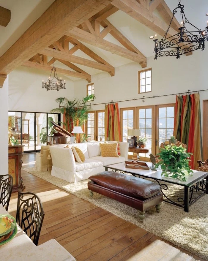 exposed wooden beams on white ceiling, farmhouse living room decor, brown leather ottoman, white sofa with throw pillows