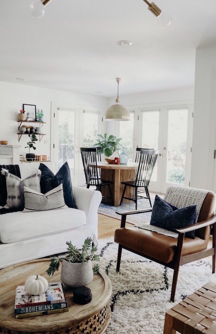 brown leather armchair, white sofa with grey and white throw pillows, farmhouse living room ideas, round wooden coffee table