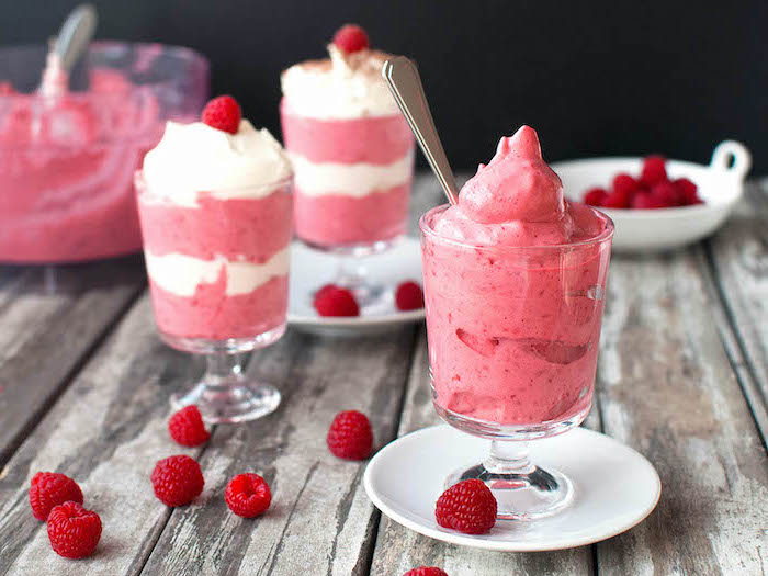 fruit mousse made with raspberries summer desserts inside glasses on white plates with spoons