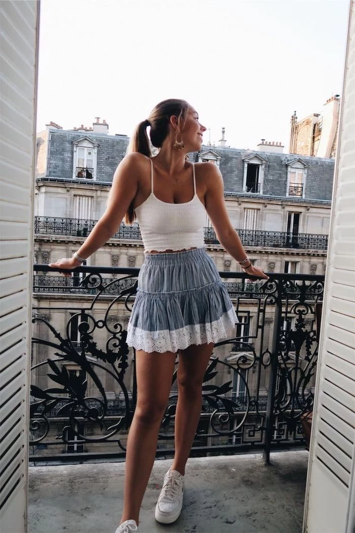 girl wearing white crop rop blue short skirt with white lace white sneakers cute casual outfits standing on a balcony