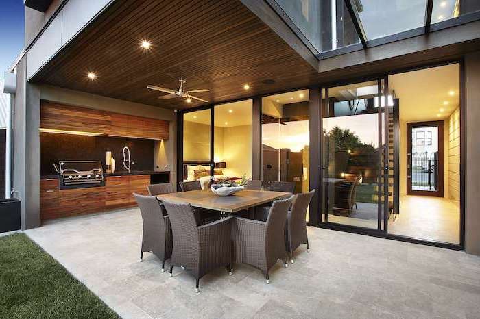 grill on wooden cabinets covered outdoor kitchen with stone tiled floor dining table surrounded by eight chairs