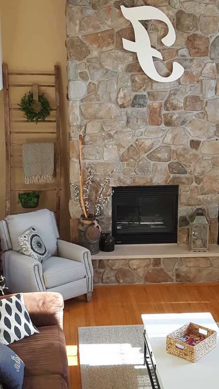 stone wall with fireplace, grey armchair, country farmhouse decor, light grey carpet on wooden floor