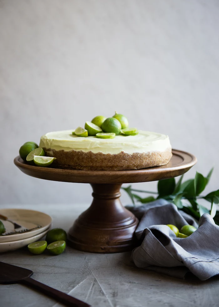 key lime tart placed on wooden cake stand picnic desserts lime slices on top and on the sides