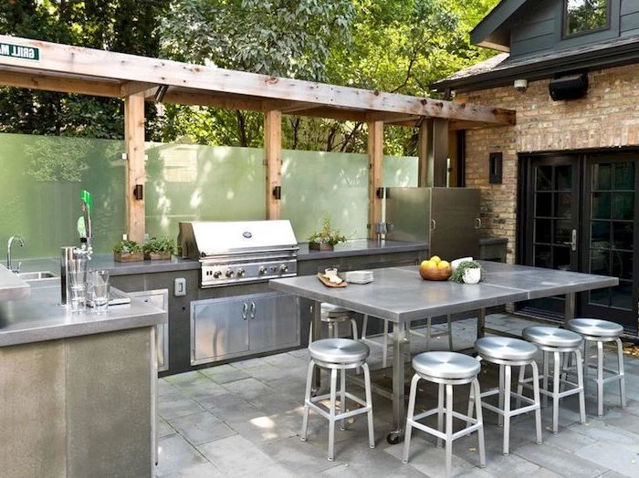 metal chairs and dining table outdoor cooking station with grill fridge sink on stone tiled floor