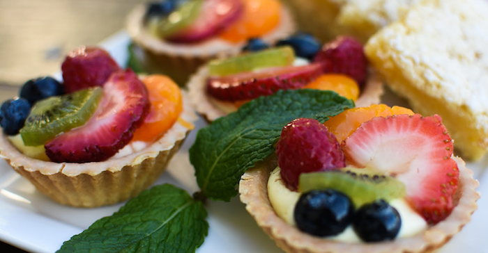no bake desserts mini tarts filled with strawberries raspberries blueberries kiwi orange mint leaves on the side