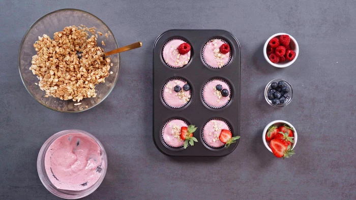 picnic desserts muffin tray with frozen skyr cupcakes ingredients in bowls on the sides on grey surface