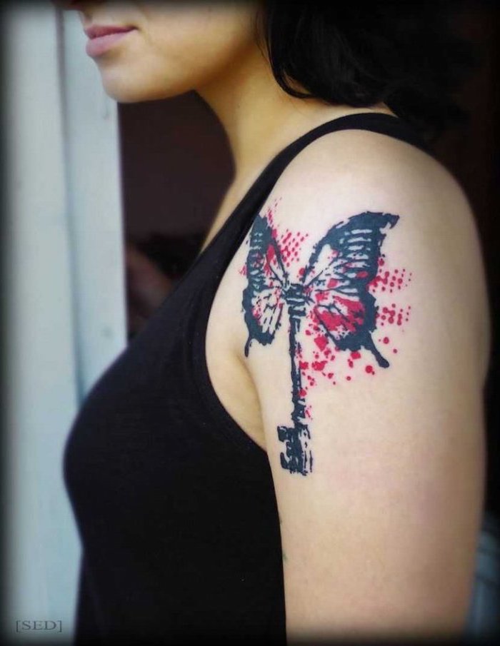 realistic trash polka tattoos butterfly key in black and red shoulder tattoo on brunette woman wearing black top