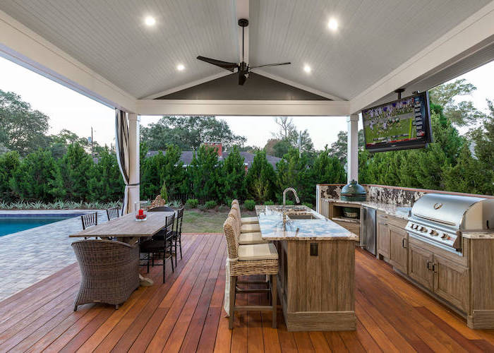 rustic outdoor kitchen next to the pool vaulted ceiling wooden floor cabinets and kitchen island with marble countertops long dining table