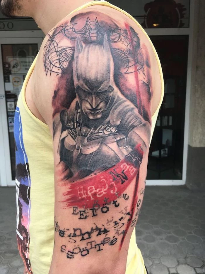 shoulder tattoo of batman trash polka tattoo words written underneath on man wearing yellow top