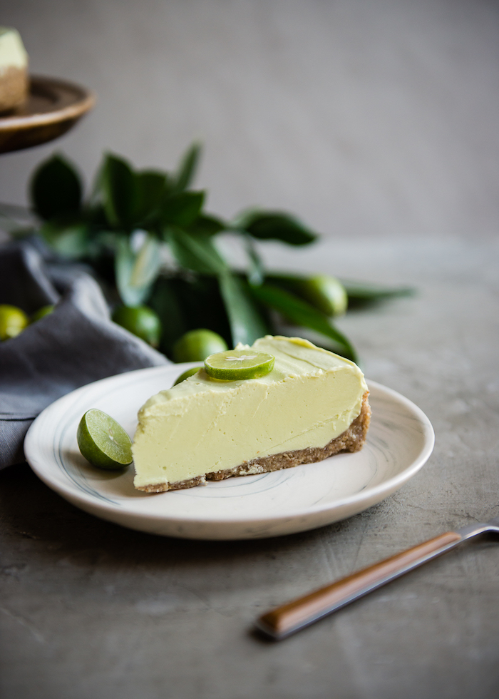 slice of key lime tart placed on white plate with lime slices on the side and on top picnic desserts