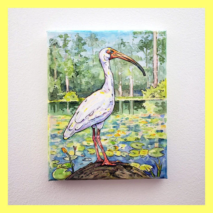 stork standing on a rock, lake with lillies, how to use watercolor, tall green trees in the background