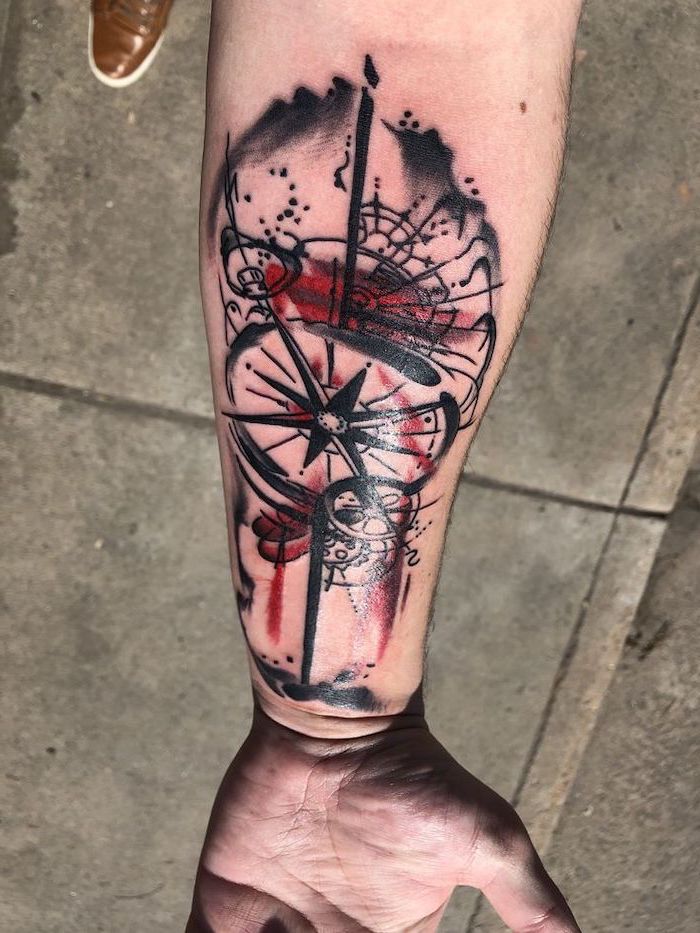 trash polka tattoo style abstract compass surrounded by black red lines forearm tattoo
