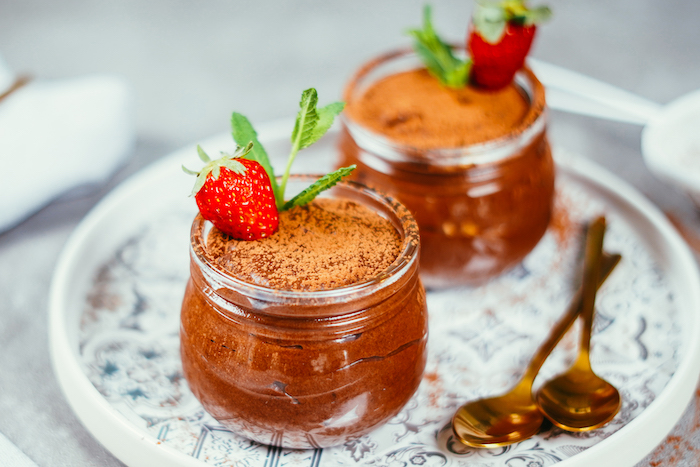 two glass jars filled with chocolate mousse easy dessert recipes no baking garnished with cacao powder strawberries and mint leaves