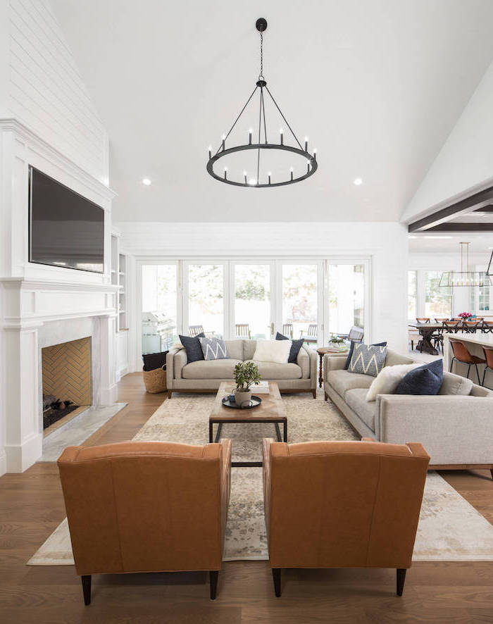 tall white walls, two brown leather armchairs, two white sofas, placed in front of a fireplace, industrial farmhouse decor