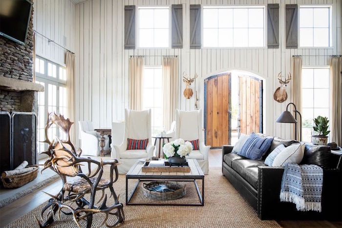 tall white wooden walls, barn door, farmhouse chic decor, black leather sofa, white armchairs, wooden coffee table