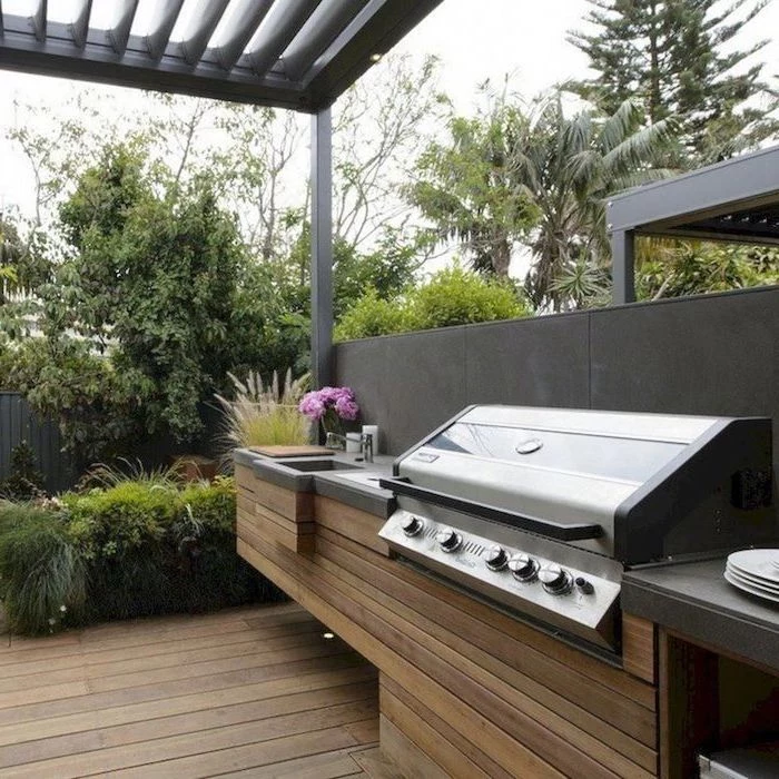 wooden cabiners under the grill grey countertop wooden floor backyard kitchen ideas surrounded by trees and bushes