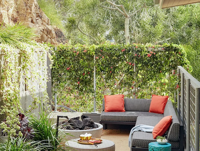 backyard paver ideas black metal garden sofa with black cushions orange throw pillows next to fire pit surrounded by greenery