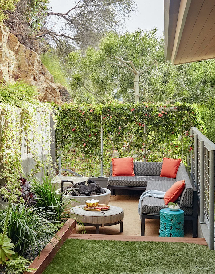 backyard paver ideas black metal garden sofa with black cushions orange throw pillows next to fire pit surrounded by greenery